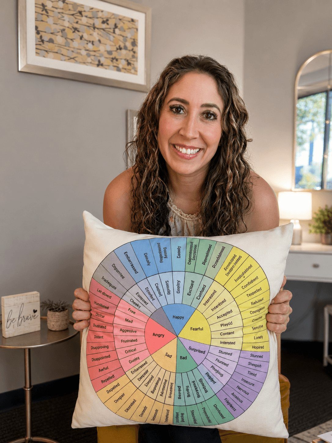 Vanessa smiling and holding a feelings-wheel pillow